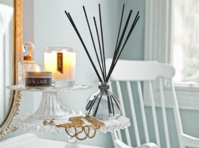 PAIRFUM luxury scented candle and natural reed diffuser on a cake stand in an English cottage